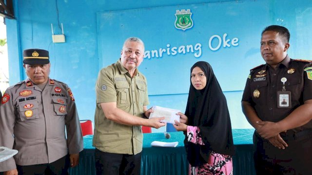 Bupati Pinrang Irwan Hamid saat menyerahkan secara simbolis bantuan keuangan kepada perwakilan korban angin puting beliung