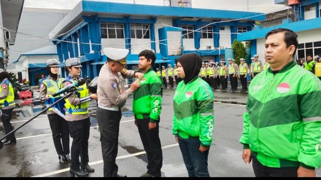 Direktur Lalu Lintas Polda Sulsel menyematkan pin &ldquo;Mappatabe&rdquo; kepada perwakilan pengemudi ojek online saat Apel Ojol Kamtibmas di Lapangan Ditlantas Polda Sulsel, Makassar, Rabu (11/2/2026).
